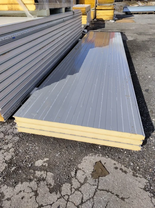 Chantier extérieur avec panneaux sandwich isolants posés au sol sur terrain industriel