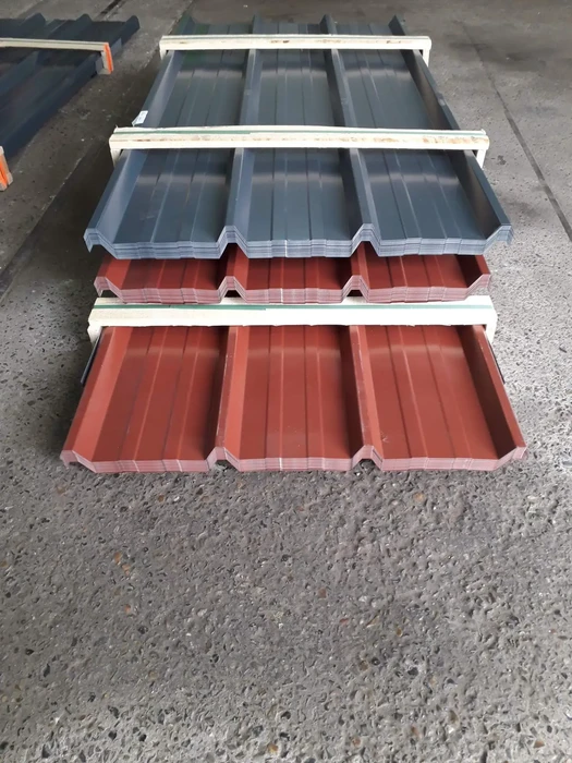 Chantier extérieur avec tôles ondulées métalliques empilées sur sol bétonné