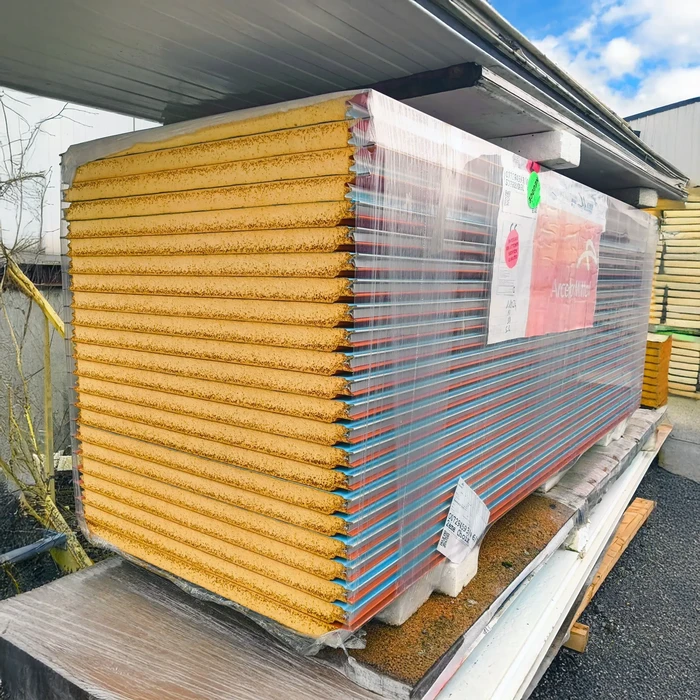 Entrepôt extérieur de matériaux de construction avec pile de panneaux isolants sandwich empilés sous film plastique protecteur