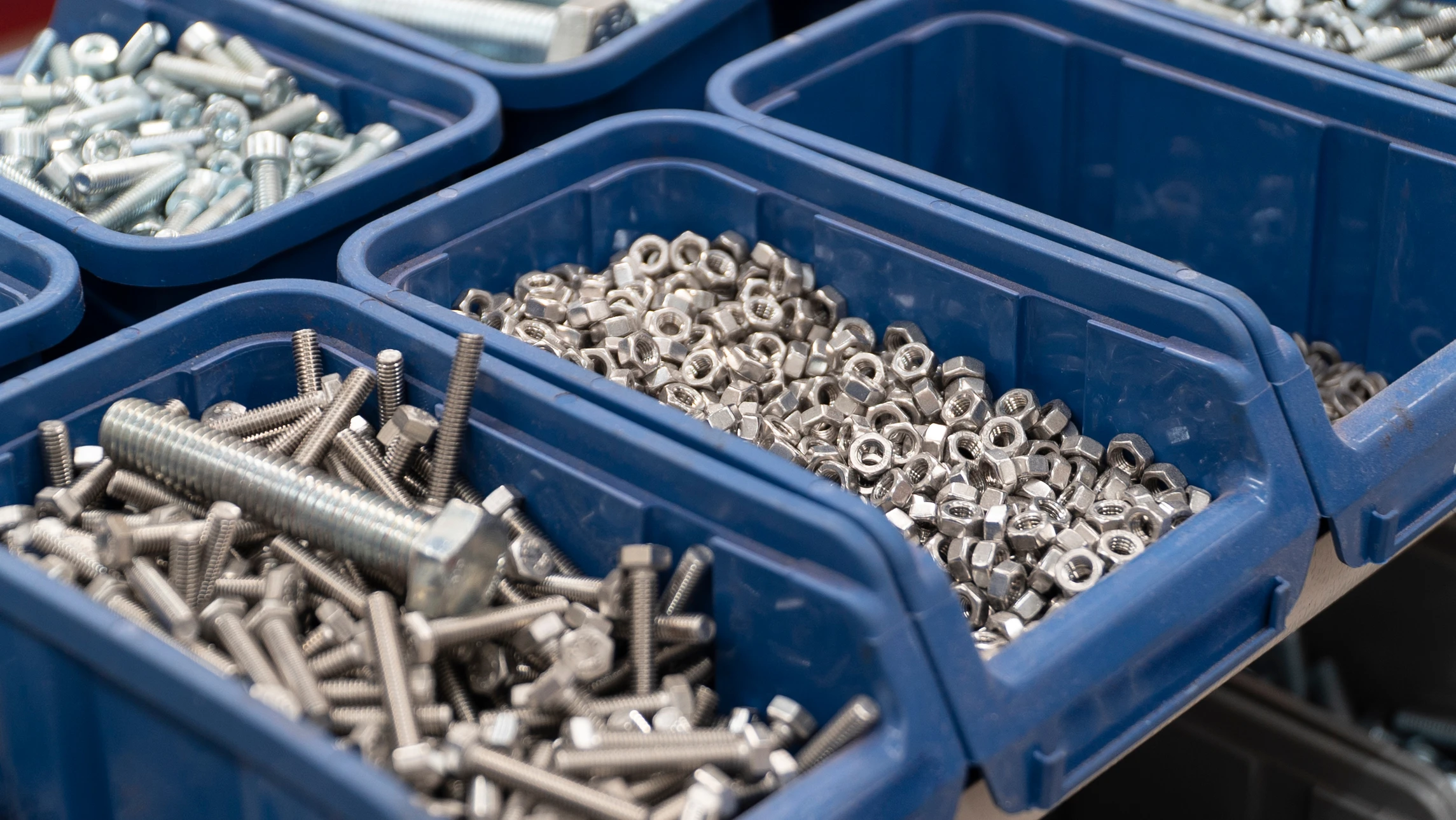 Intérieur d'atelier ou magasin de bricolage avec boîte de rangement compartimentée contenant diverses vis et fixations métalliques